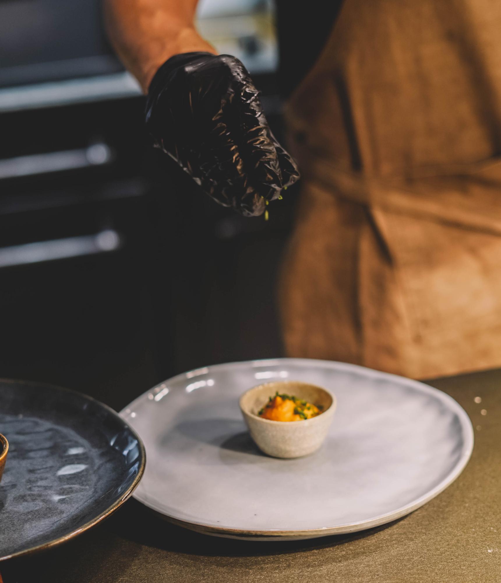 Chef arranging plated tasting menu on wooden counter